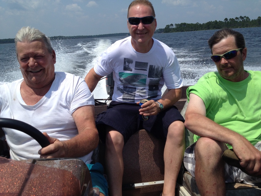 Three men in a small boat speeding across open water, wake behind them. I'm in the middle.